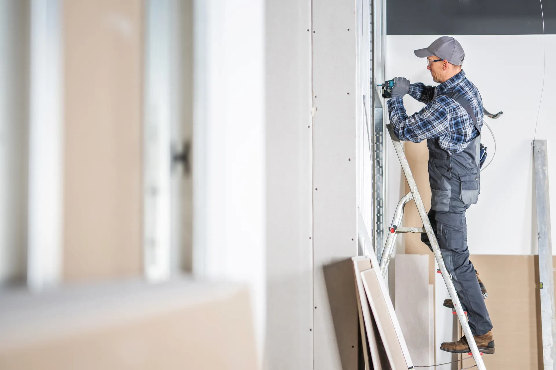 Monteur montiert eine Brandschutzwand auf der Leiter – fachgerechter baulicher Brandschutz auf der Baustelle in der Schweiz