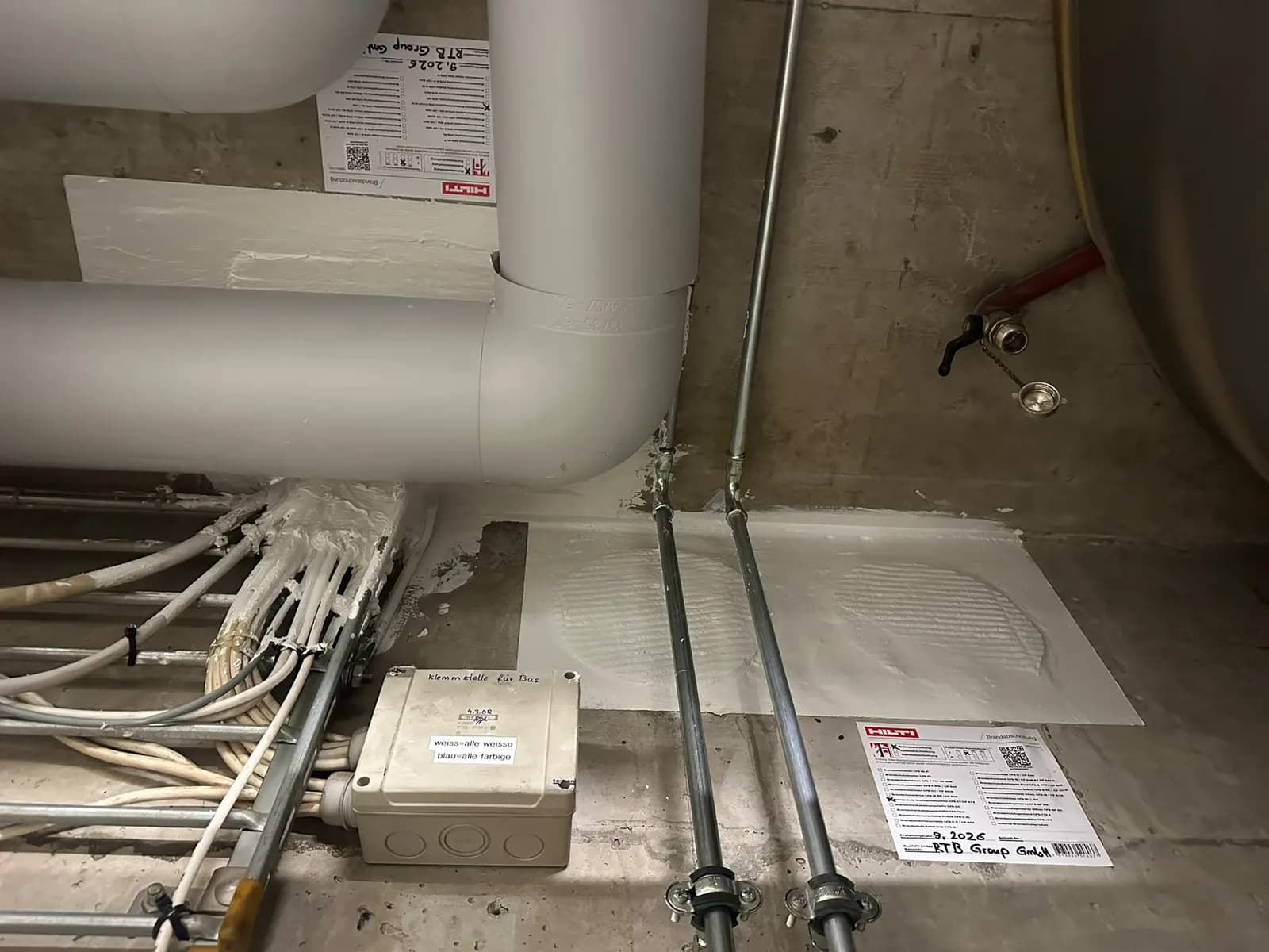 Ausgeführte Brandabschottungen an einer Betondecke: Weichschott für Kabel- und Rohrdurchführungen mit Schottkennzeichnung der RTB Group GmbH